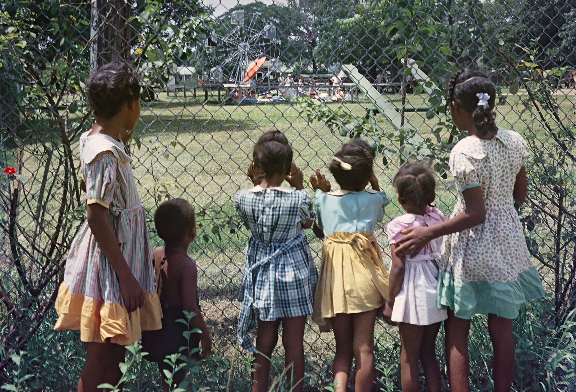 Пример расовой сегрегации. Афроамериканские дети смотрят через забор на игровую площадку, доступ на которую для них запрещён законом. Алабама. 1956 год. Гордон Паркс/Getty Images.
